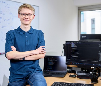Junger Mann sitzt lässig auf seinem Schreibtisch
