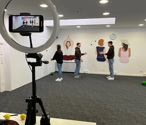 Auszubildende entwickeln Übungen für eine aktive Pause und werden dabei gefilmt.