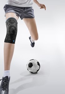 A person with knee pads tries to kick a ball.