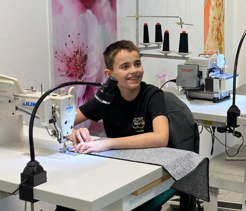 Ein Jugendlicher sitzt an einer Nähmaschine