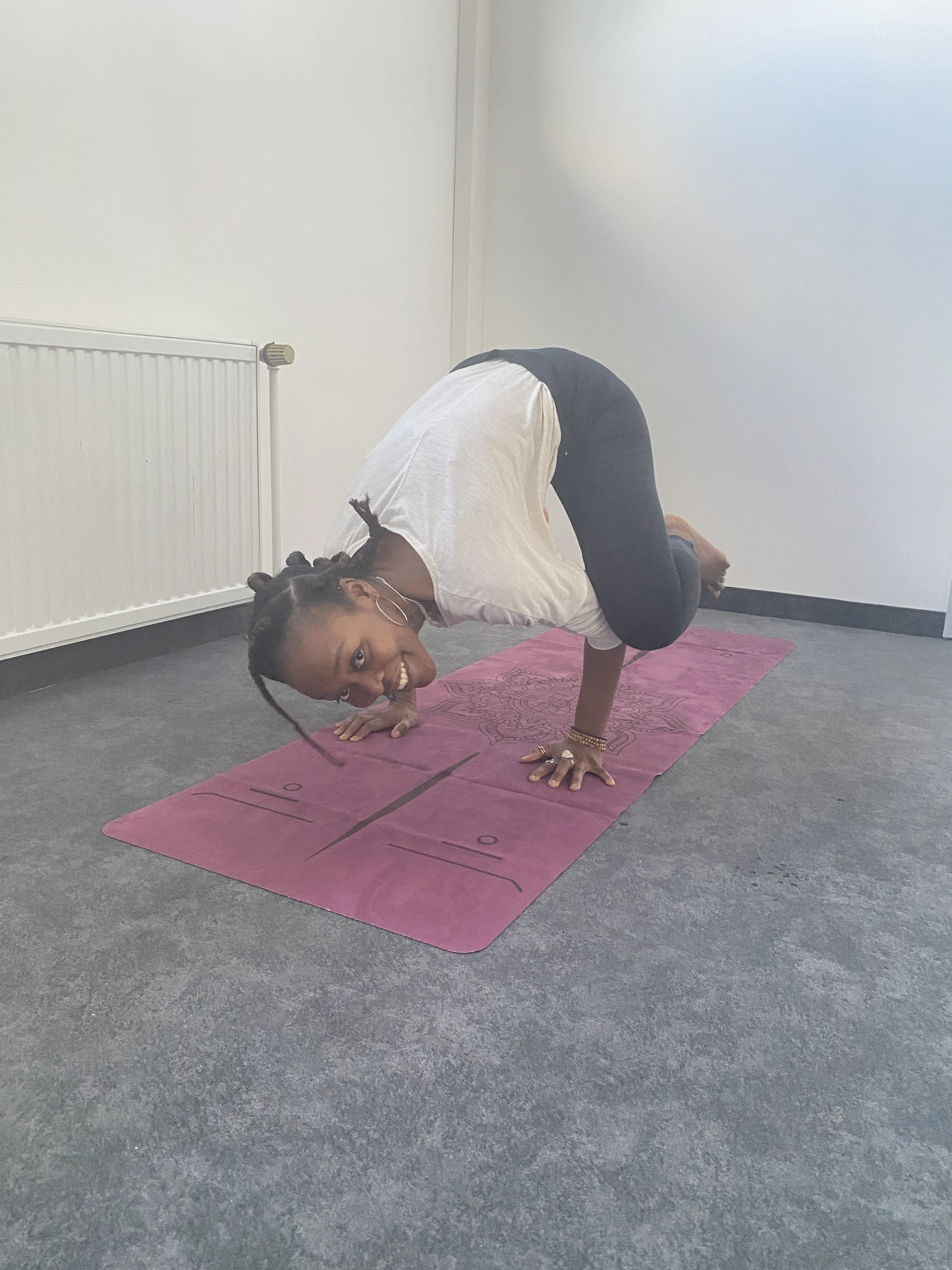 Frau in der Yogapose Krähe auf einer Yogamatte