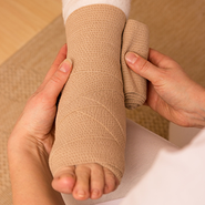 Compression bandages are applied to a foot.