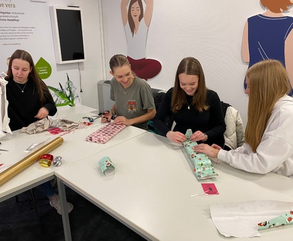 4 Jugendliche sitzen an einem Tisch und packen Geschenke ein.