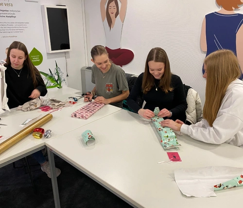 4 Jugendliche sitzen an einem Tisch und packen Geschenke ein.