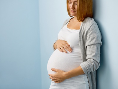 Schwangere Frau hält sich den Bauch