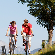 A couple ride their bikes outside.