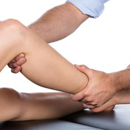 A physiotherapist massages a patient's leg.