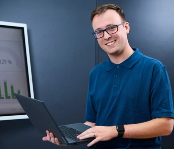 Junger Mann in einem Büro mit Laptop in der Hand