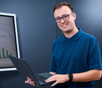 Junger Mann in einem Büro mit Laptop in der Hand