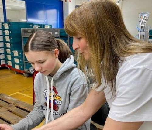 Frau zeigt einem Mädchen einen Kompressionsstrumpf