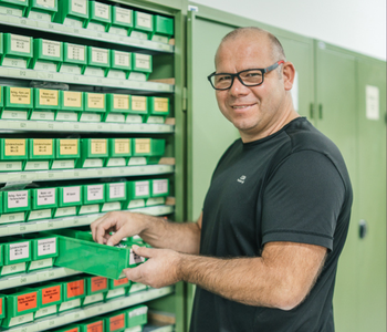Mitarbeiter in der Werkstatt steht vor einem Materialschrank