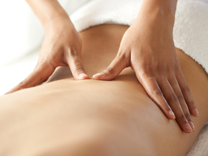 A woman massages somebody's back.