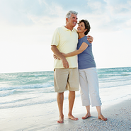 An older couple walk on the beach.